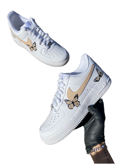 White sneakers with hand-painted butterflies in beige and peach tones. Checkmark painted beige