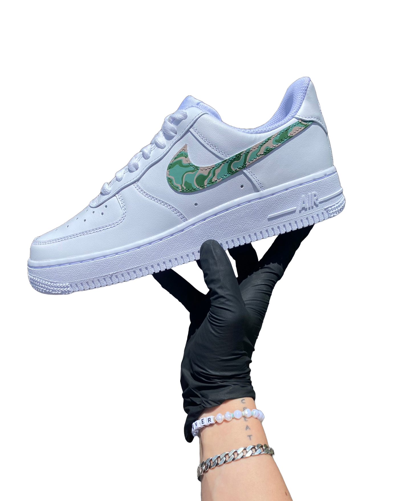 Artist's hand holding hand-painted spiraldesign on what would otherwise be a white pair of Air Force 1's. Colors include moss green, forest green and biege. Angle 2.